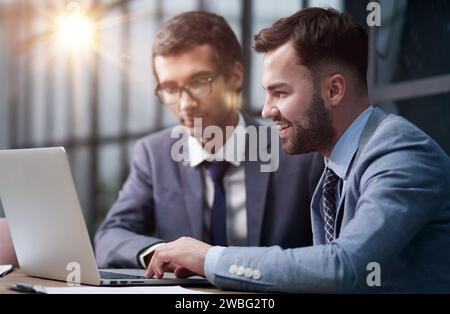 Two handsome businessmen working together on a project sitting Stock Photo