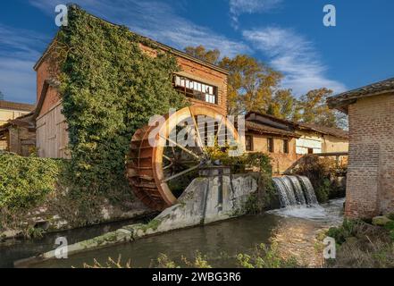 Old disused paddle mill with rusted iron wheel near a canal in the Po Valley in Piedmont, Italy Stock Photo