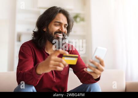 Positive indian guy enjoying newest shopping application Stock Photo