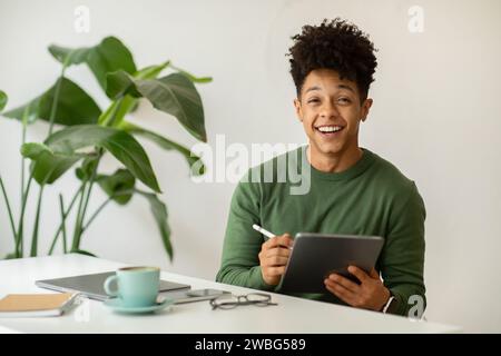 Happy african american guy designer working at cafe Stock Photo
