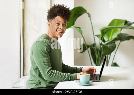 Positive millennial african american man IT employee working at cafe Stock Photo