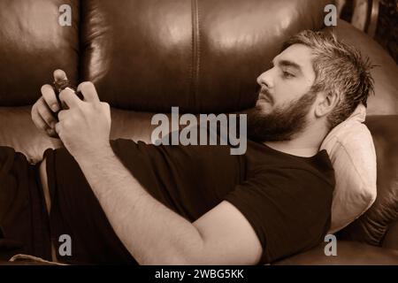 Happy guy using smartphone, enjoying leisure at home Stock Photo
