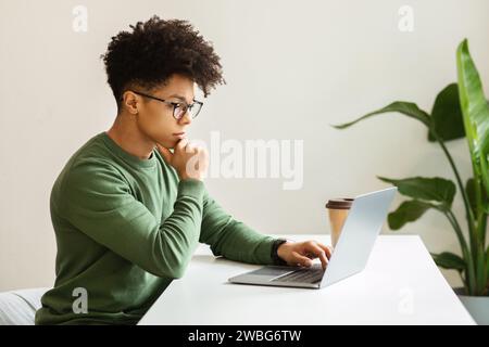 Concentrated young black guy freelancer working from cozy cafe Stock Photo