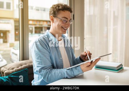 Cheerful millennial european guy designer in glasses using pen and digital tablet for paint Stock Photo