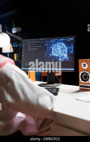 Arab guy works on a computer, utilizing AI, coding, and cyber security. He monitors data on a desktop pc screen, controlling a powerful cloud-based system. Over-the-shoulder shot. Stock Photo