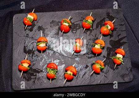 shale stone board with slices of cherry tomatoes and mozzarella cheese Stock Photo