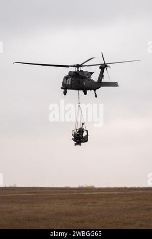 Artillery Soldiers with Alpha 'Gator' Battery, 3rd Battalion, 320th Field Artillery Regiment, 3rd Brigade Combat Team, 101st Airborne Division, 'Task Force 82,' conduct sling-load training at Mihail Kogalniceanu Air Base, Romania, Jan. 9, 2024. UH-60 Black Hawk helicopters from the 3rd Attack Helicopter Battalion, 1st Aviation Regiment, 1st Combat Aviation Brigade, 1st Infantry Division, supported the 101st Airborne Division Artillery Soldiers by moving M119 howitzers by air to increase proficiency in their warfighting tasks. (U.S. Army photo by Sgt. 1st Class Jonathan Hornby) Stock Photo