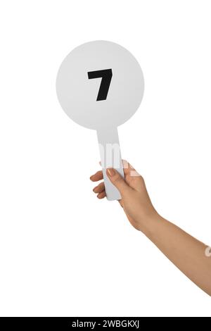 Woman holding auction paddle with number 7 on white background, closeup Stock Photo