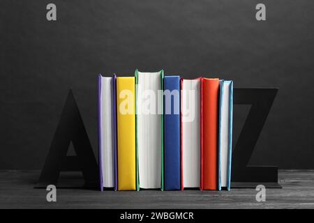 Letter bookends with different books on gray wooden table Stock Photo