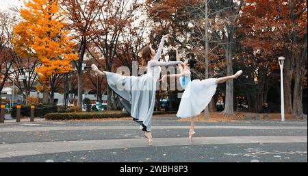 Ballet, dancing and women in autumn on the street in Japan park with pointe shoes and creative pose. Outdoor, ballerina and people with performance of Stock Photo