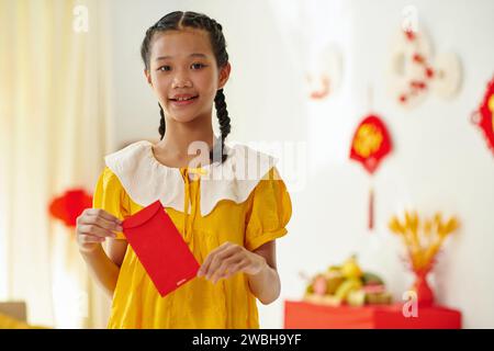 Portrait of Vietnamese teenage girl holding red lucky money envelope Stock Photo