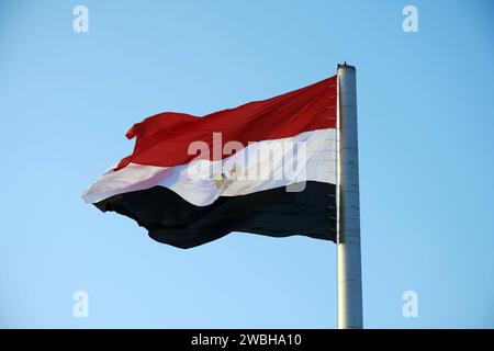 A large flag of Egypt on a flagpole against a blue sky Stock Photo