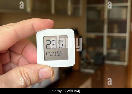 Comfortable humidity and temperature in the apartment. Close-up of a man's hand holding a hygrometer and thermometer. Stock Photo