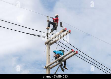 Electricians working on power pole connecting cables Stock Photo