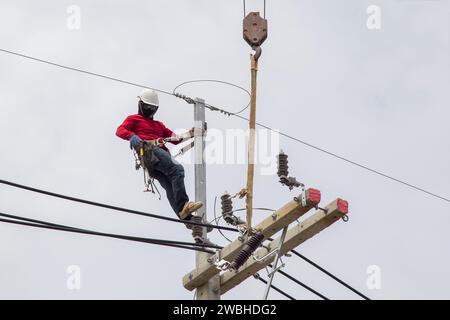 Electricians working on power pole connecting cables Stock Photo