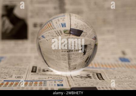 A glass globe reveals the letters inside, with a newspaper in the background. Stock Photo