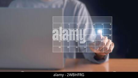 Businessman using pen to set meeting agenda on calendar as appointment planning concept Stock Photo