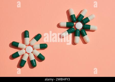 Creative scene for advertising with pharmacy theme. Two flowers are arranged from capsules pills on a pink background. Healthcare and medicine concept Stock Photo