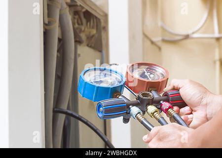Air repair mechanic using measuring equipment for filling industrial factory air conditioners. Stock Photo
