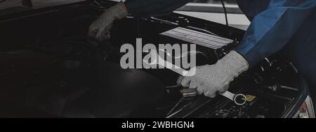 Mechanic works on the engine of the car in the garage.Concept of car inspection service and car repair service. Stock Photo