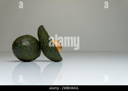 Captivating photograph featuring a fresh avocado placed on a white table in a minimalist setting, highlighting its vibrant and healthy taste Stock Photo