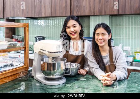 Small startup business owner concept. two successful young asian entrepreneurs women standing in bar counter in cafe bakery department. Stock Photo