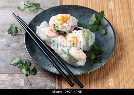 Vietnamese spring rolls with vegetables, rice noodles and prawns on wooden table Stock Photo