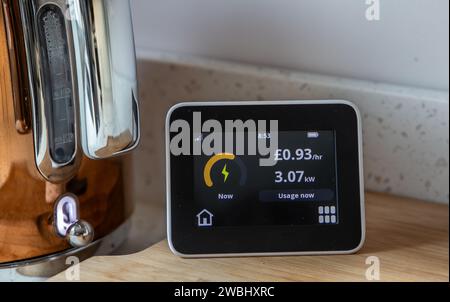 Remote smart meter display showing electricity use with the kettle on.Cost of living. Stock Photo