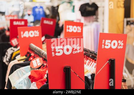Red discount signs on clothes racks in a clothing store. Stock Photo