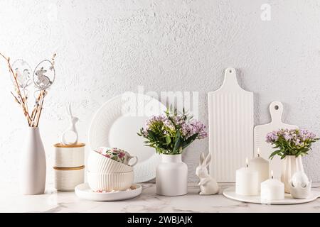 Chic kitchen background in delicate pastel colors, decorated for the Easter holiday with rabbits, candles, flowers, eggs. White cookware Stock Photo