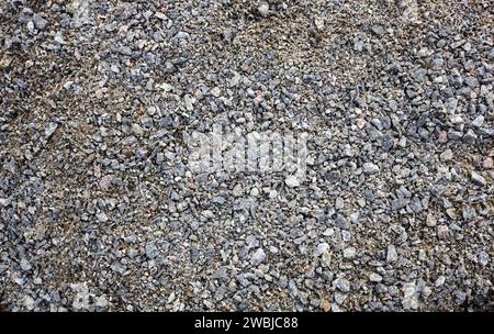 Grey ground stone rubble road background. Natural gray granite chippings, macadam, rubble or crushed stones texture, top view Stock Photo