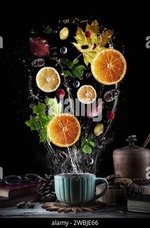 Tea splash composition on a black background. Slices of lemon, orange, ginger, mint, cones and acorns, autumn leaves and raspberries are placed in spl Stock Photo