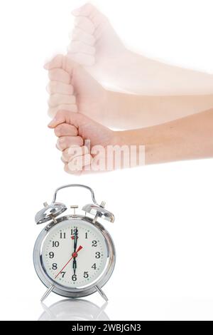 Person, hand and hitting alarm clock for alert, wakeup or deadline on a white studio background. Closeup of fist slamming down on time for stop in Stock Photo