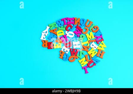 Human brain shape made from colorful wooden letters, arranged on a light blue background. Vibrant learning and education related concept. Stock Photo