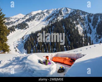 Overnight in the mountains in winter. A man sleeps in a sleeping bag in a snowy shelter. Multiday hikes in winter Stock Photo