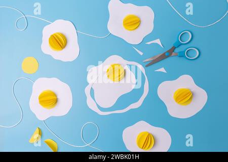 three fried eggs paper craft hanging from a string on a blue background, easter decoration concept,  Stock Photo