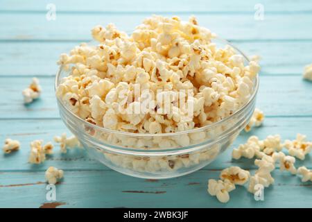 Fresh popcorn in bowl on blue table. Top view Stock Photo