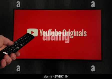 Nikolaev, Ukraine - November 20, 2021. Man with TV remote control in hand and YouTube logo in background. YouTubeis the global provider of streaming m Stock Photo