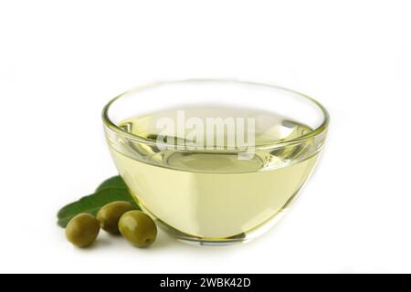 Bowl of fresh extra virgin olive oil and green olives with leaves isolated on white background. Stock Photo