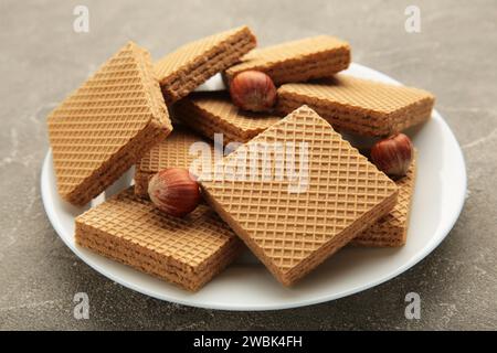 Square chocolate wafer biscuits with hazelnut on white plate on grey background. Top view. Stock Photo