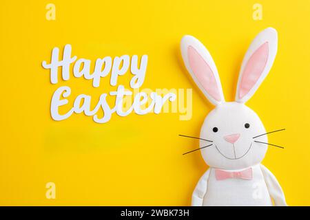 Happy easter, Happy Easter Greeting with Cartoon Bunny on Bright Yellow Background and Playful White Cursive Font Stock Photo