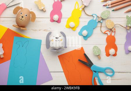 Easter bunnies handmade from colored paper, easy crafts for kids on a white background. Top view. Stock Photo