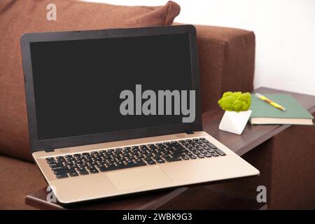 Work from home concept: laptop computer with blank black screen on brown sofa bed. Top view Stock Photo