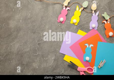Easter bunnies handmade from colored paper, easy crafts for kids on a grey background. Stock Photo