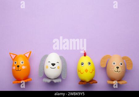 Easter holiday concept with cute handmade eggs, dogs, chicks and cat on purple background. Top view. Happy Easter Stock Photo