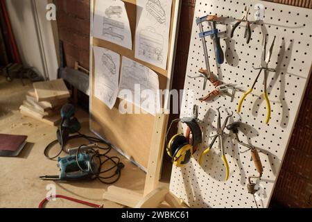 Close up of carpenters tools on pegboard in workshop lit by sunlight, copy space Stock Photo