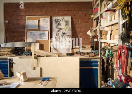 Wide angle view at carpentry workshop in sunlight with various tools and wooden models on table Stock Photo