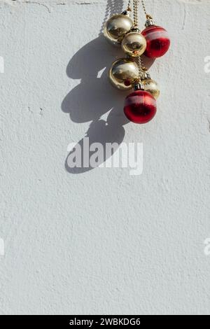 Red and gold Christmas tree baubles hanging on a white house wall in Spain Stock Photo