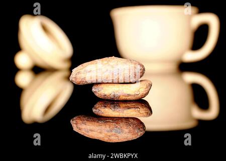 Several dry cocoa beans in a ceramic cup, macro, isolated on black background. Stock Photo