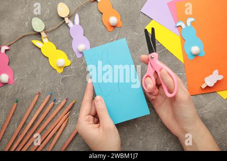 DIY and kid's creativity. How to make paper greeting cards with a bunny, cut out blanks from multi-colored paper. (Sheets of colored paper, scissors). Stock Photo